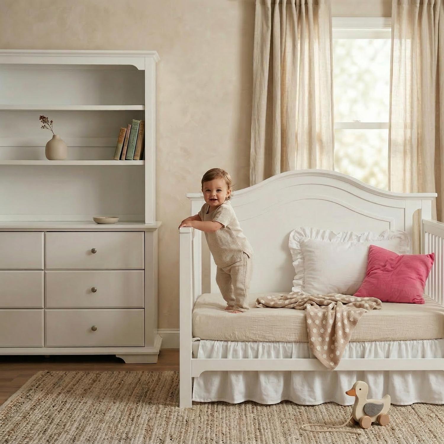 White toddler daybed with a dresser and bookshelf hutch in a cream nursery