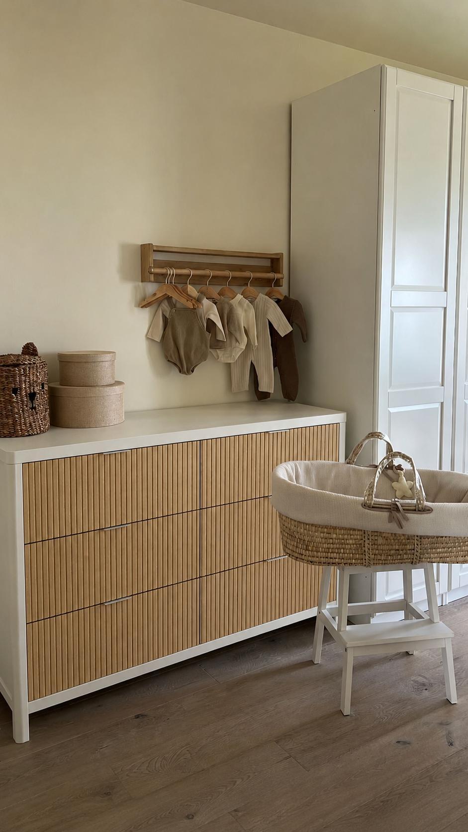 White and natural wood six-drawer dresser with a Moses basket on a stand